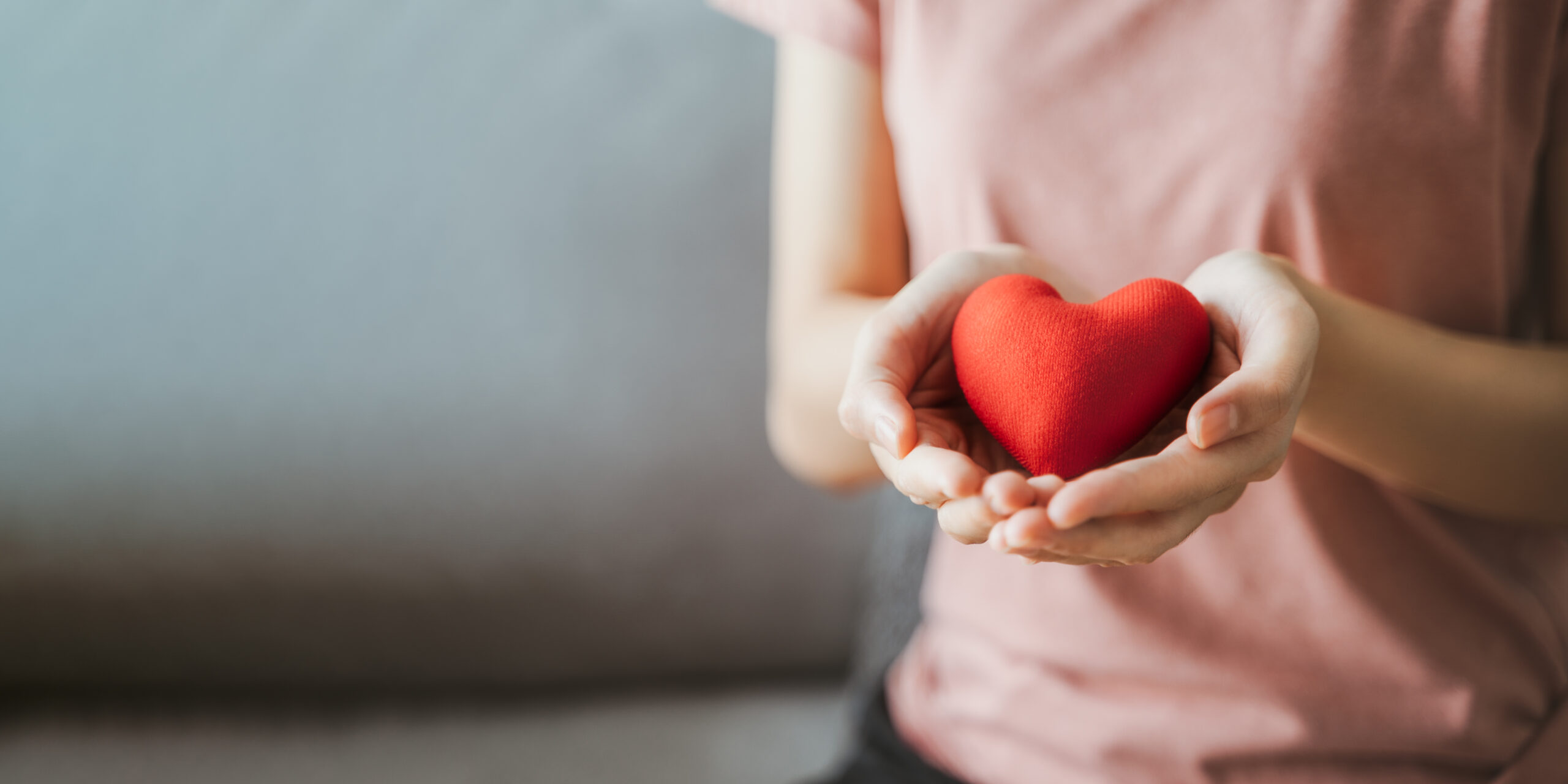 A woman holding a red heart in hands